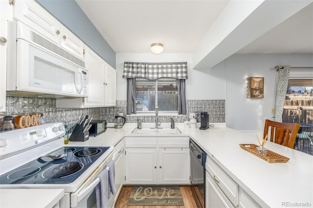 kitchen featuring white appliances, white cabinetry, light countertops, and a sink