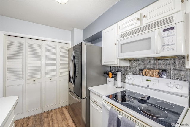 kitchen with light countertops, light wood-style flooring, decorative backsplash, white cabinets, and white appliances