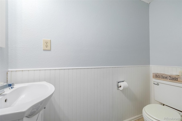 bathroom featuring wainscoting, a sink, and toilet