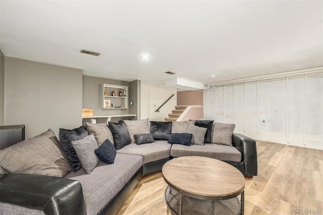 living room featuring light wood finished floors, stairs, and visible vents