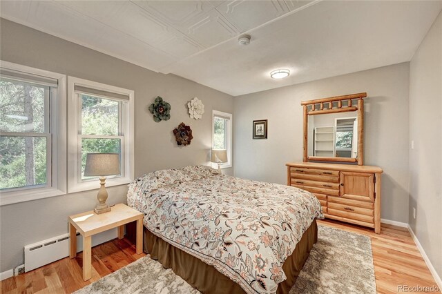 4642 Plettner Ln, Evergreen, CO 80439 - bedroom with multiple windows, a baseboard radiator, light wood-style floors, and baseboards