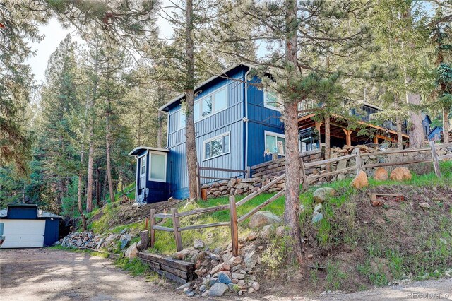 4642 Plettner Ln, Evergreen, CO 80439 - view of front of home with fence, an outbuilding, and a forest view