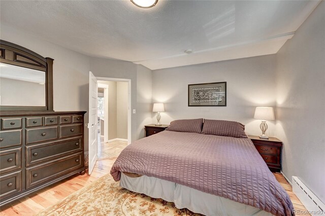 4642 Plettner Ln, Evergreen, CO 80439 - bedroom with a baseboard heating unit, light wood-type flooring, and baseboards