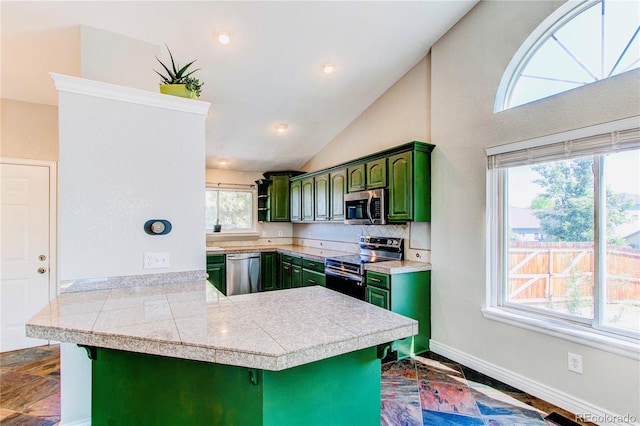 kitchen featuring stainless steel appliances, green cabinets, a peninsula, tile countertops, and healthy amount of natural light