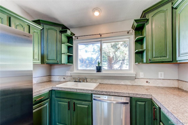 kitchen with stainless steel appliances, open shelves, a sink, green cabinets, and a textured ceiling
