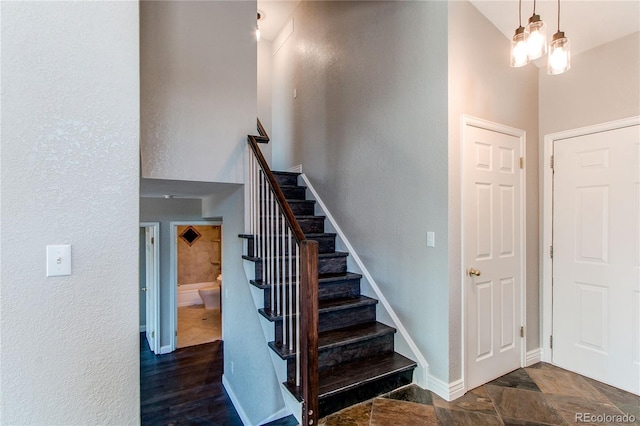 stairs featuring a towering ceiling, baseboards, and a textured wall