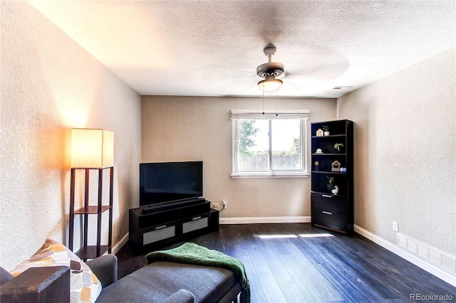 sitting room with a textured wall, dark wood finished floors, baseboards, and a textured ceiling