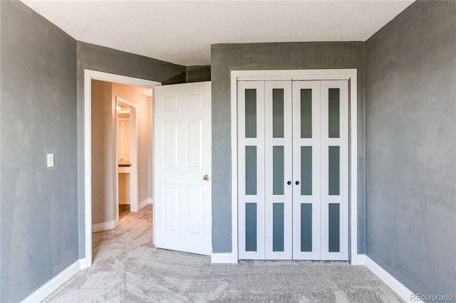 unfurnished bedroom with carpet, a closet, and baseboards