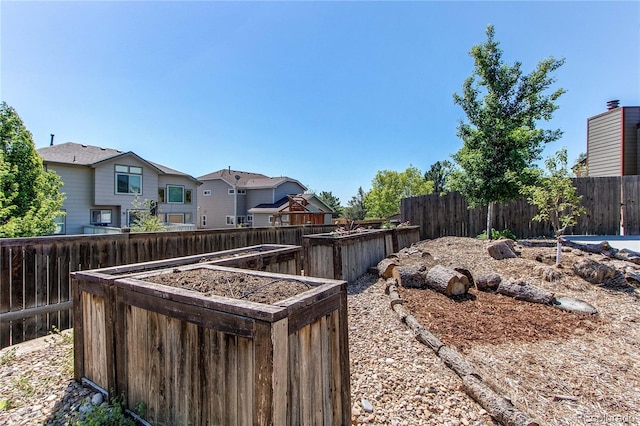 view of yard featuring fence, a garden, and a residential view