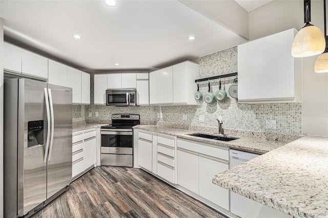 kitchen with pendant lighting, stainless steel appliances, white cabinets, a sink, and modern cabinets