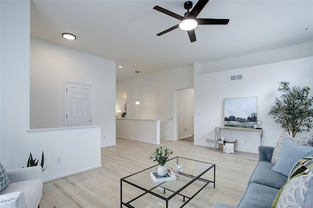 living room with light wood-type flooring, visible vents, and arched walkways