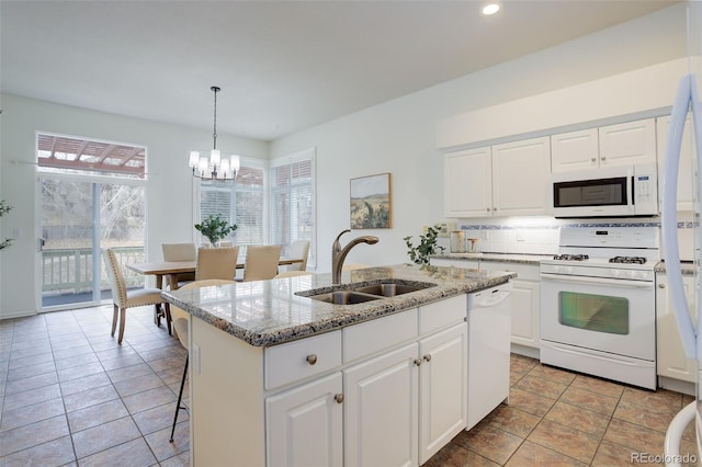 kitchen featuring backsplash, white cabinets, a sink, light stone countertops, and white appliances