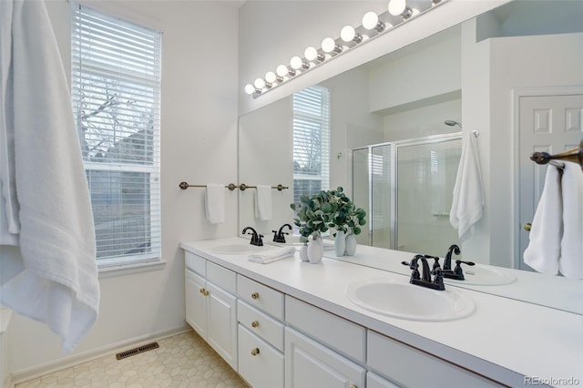 full bath featuring a stall shower, visible vents, a sink, and double vanity