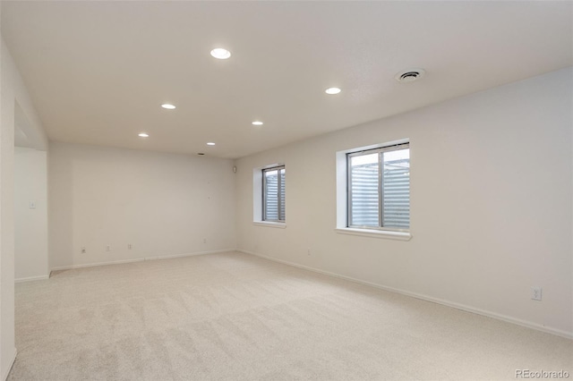 spare room featuring light colored carpet, visible vents, baseboards, and recessed lighting