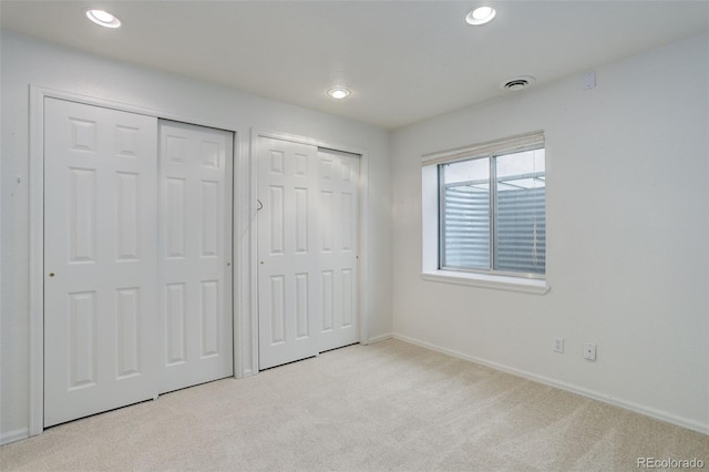 unfurnished bedroom with recessed lighting, visible vents, baseboards, carpet, and two closets