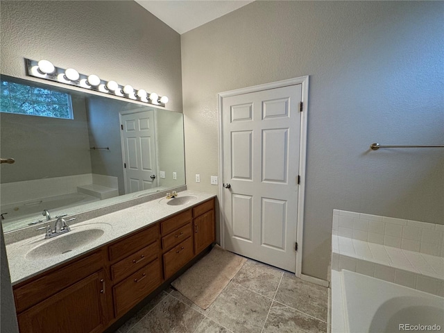 full bathroom featuring a garden tub, a sink, a textured wall, and double vanity