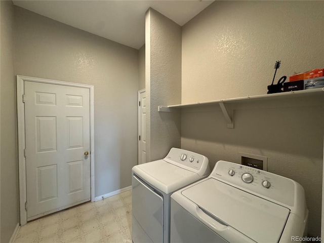 washroom with laundry area, baseboards, light floors, a textured wall, and washer and clothes dryer