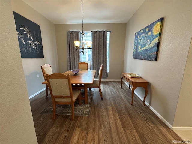 dining area with a textured wall, baseboards, a notable chandelier, and dark wood-style floors