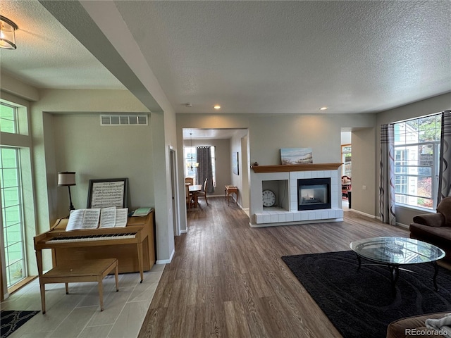 living room featuring visible vents, baseboards, recessed lighting, a textured ceiling, and light wood-style flooring