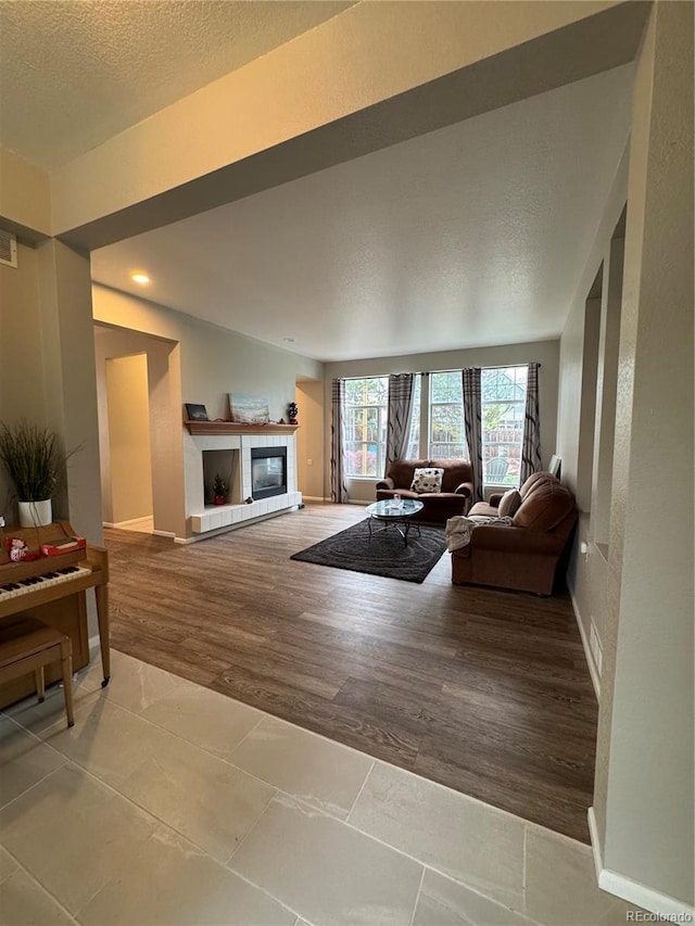 living room with baseboards, a textured ceiling, wood finished floors, and a fireplace