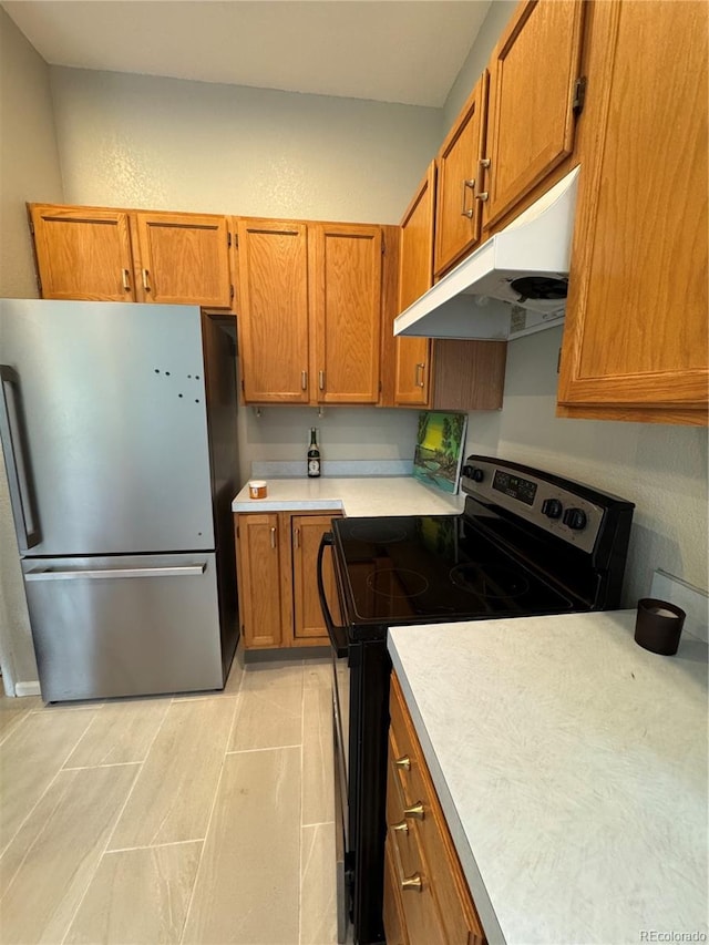 kitchen with under cabinet range hood, stainless steel appliances, brown cabinetry, and light countertops