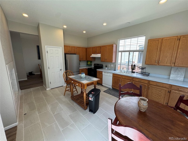 kitchen featuring freestanding refrigerator, white dishwasher, electric range oven, under cabinet range hood, and a sink