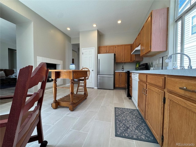 kitchen featuring brown cabinetry, freestanding refrigerator, stove, recessed lighting, and under cabinet range hood