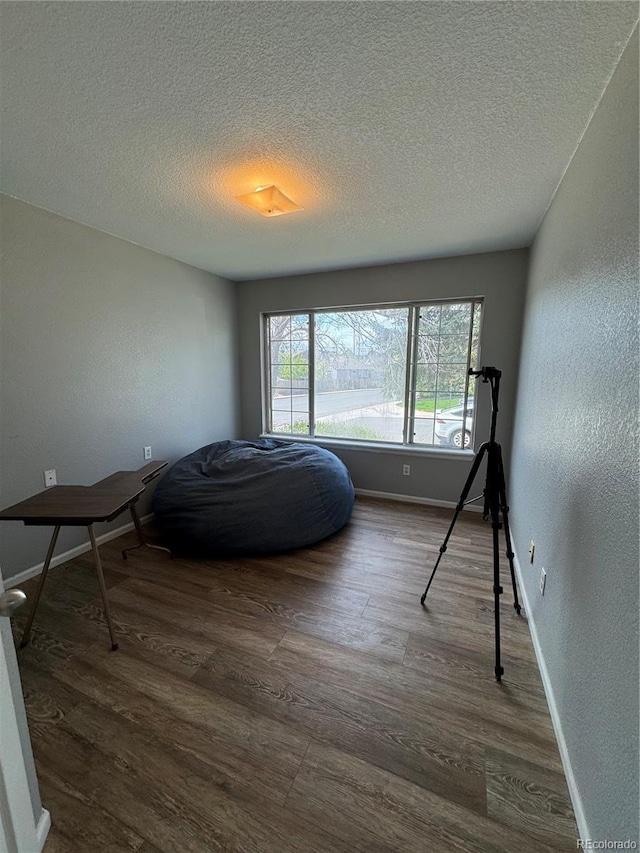 bedroom featuring multiple windows, dark wood-style flooring, and a textured ceiling