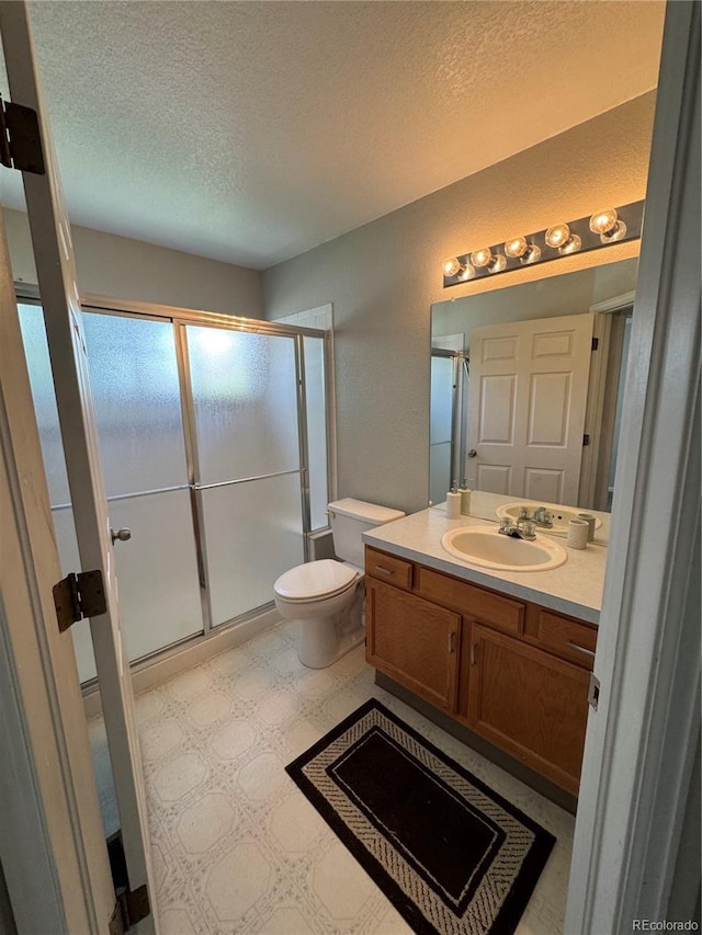 bathroom with vanity, toilet, a textured ceiling, tile patterned floors, and a shower stall
