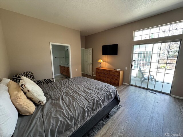 bedroom with access to outside, baseboards, wood finished floors, and visible vents
