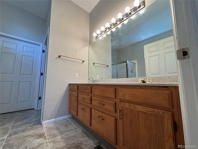 bathroom featuring a sink, double vanity, baseboards, stone finish flooring, and a shower stall