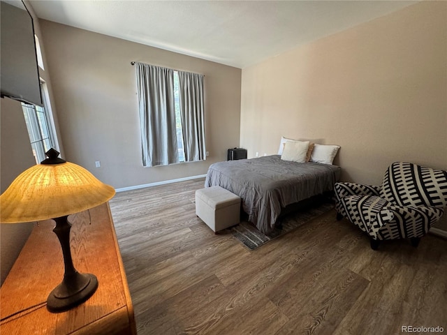 bedroom with baseboards, wood finished floors, and multiple windows