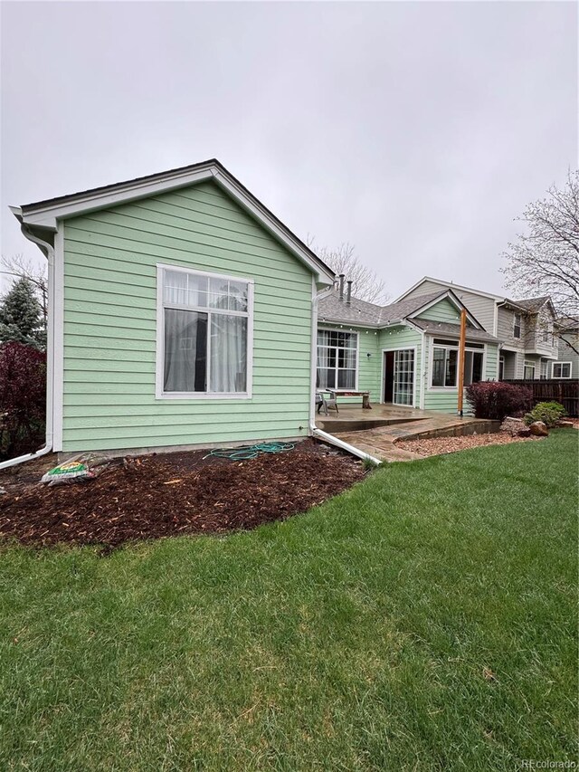rear view of property featuring a lawn and a patio area