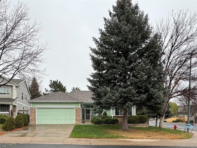 view of front of house featuring driveway, a front yard, a garage, brick siding, and a shingled roof
