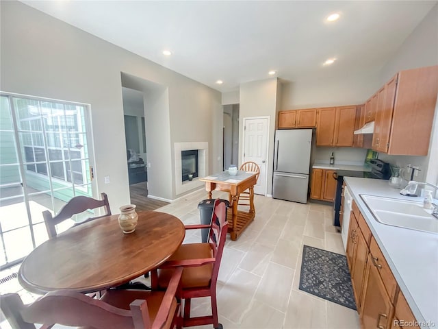 9806 Hooker Ct, Westminster, CO 80031 - kitchen featuring appliances with stainless steel finishes, a sink, under cabinet range hood, light countertops, and a fireplace