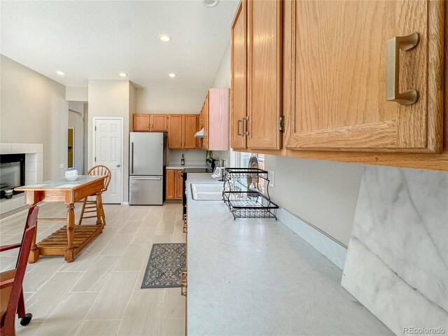 9806 Hooker Ct, Westminster, CO 80031 - kitchen featuring stainless steel refrigerator, light countertops, brown cabinets, recessed lighting, and a tiled fireplace