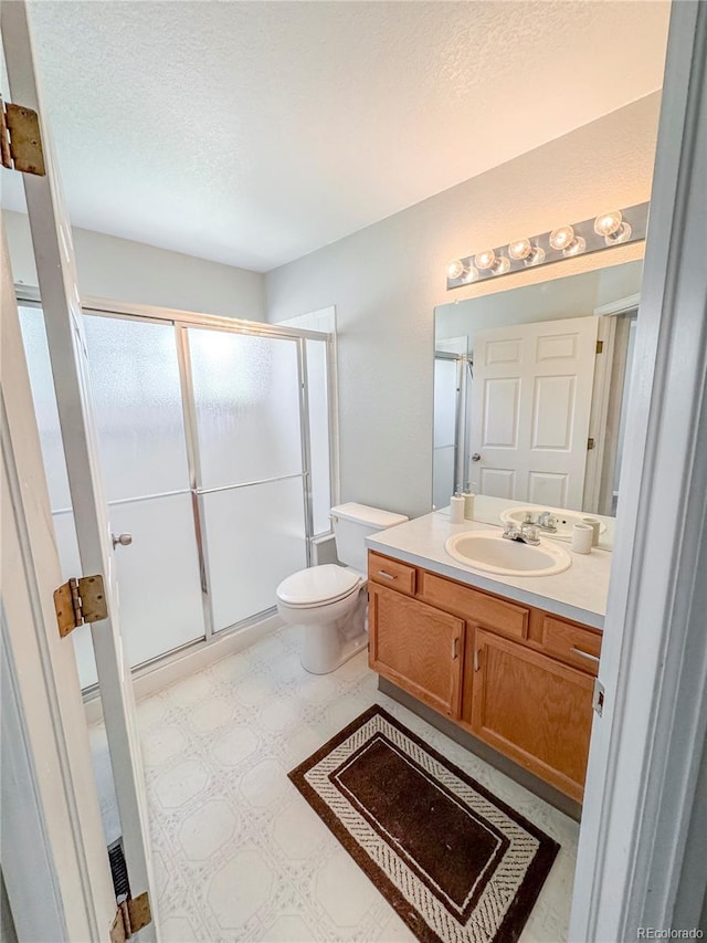 9806 Hooker Ct, Westminster, CO 80031 - bathroom featuring a stall shower, tile patterned floors, vanity, a textured ceiling, and toilet