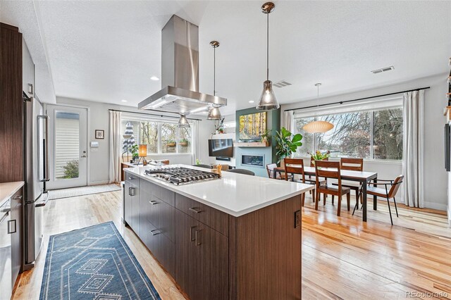 kitchen with a kitchen island, visible vents, island range hood, appliances with stainless steel finishes, and light wood-style flooring