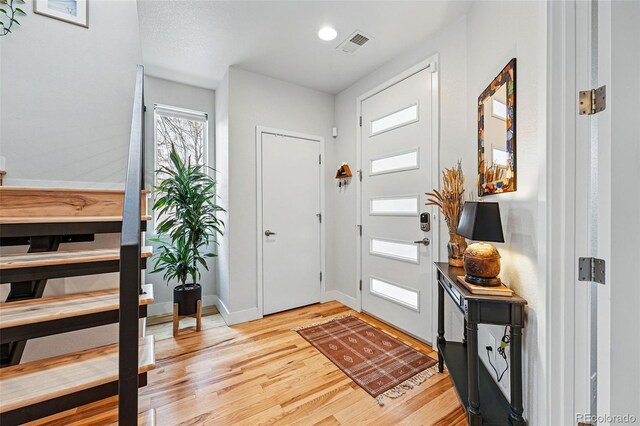 foyer featuring light wood-type flooring, baseboards, and visible vents