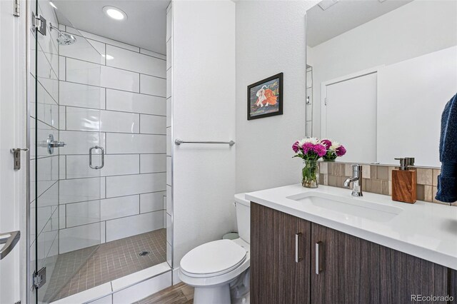 bathroom featuring vanity, toilet, recessed lighting, a shower stall, and wood finished floors
