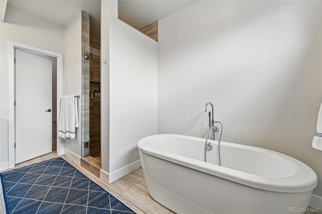 full bath with baseboards, a shower stall, and a soaking tub