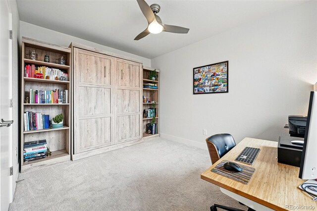 carpeted home office with ceiling fan and baseboards