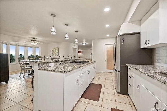 kitchen with a kitchen bar, ceiling fan, decorative light fixtures, and white cabinetry