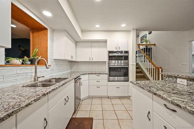 kitchen with white cabinetry, sink, decorative backsplash, appliances with stainless steel finishes, and light tile patterned flooring