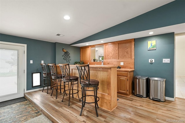 bar with vaulted ceiling and light hardwood / wood-style flooring