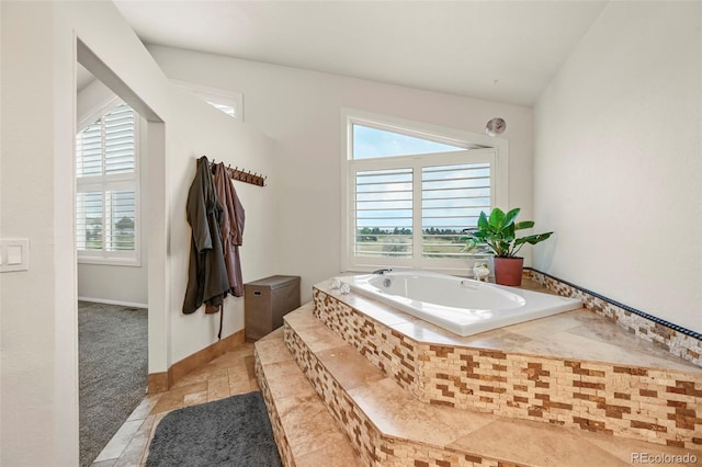 bathroom featuring tiled tub and vaulted ceiling