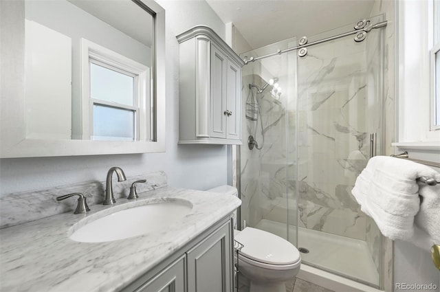 bathroom featuring vanity, toilet, and a shower with shower door