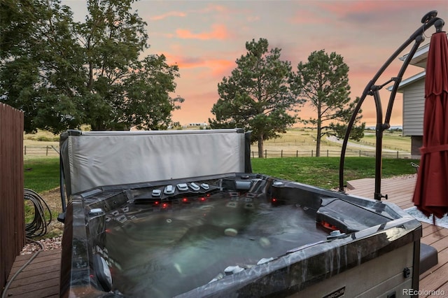 deck at dusk with a hot tub and a yard