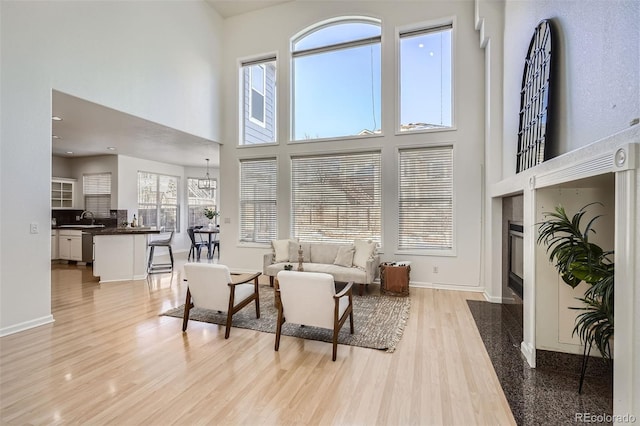 living room with light hardwood / wood-style flooring, a high end fireplace, a high ceiling, and sink