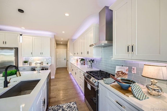 kitchen featuring white cabinets, wall chimney exhaust hood, pendant lighting, and stainless steel appliances